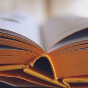 Vista de primer pla d'un llibre obert amb pàgines amb vores grogues, que mostra el llom i un text lleugerament borrós, cosa que suggereix llegir o estudiar amb una llum suau; perfecte per a aquells que utilitzen llenties progressives o compren llenties en línia.