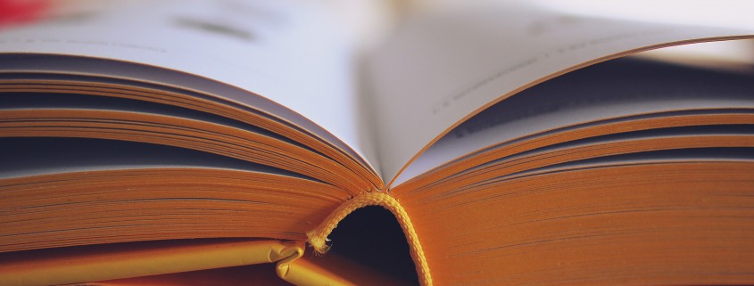Vista de primer pla d'un llibre obert amb pàgines amb vores grogues, que mostra el llom i un text lleugerament borrós, cosa que suggereix llegir o estudiar amb una llum suau; perfecte per a aquells que utilitzen llenties progressives o compren llenties en línia.